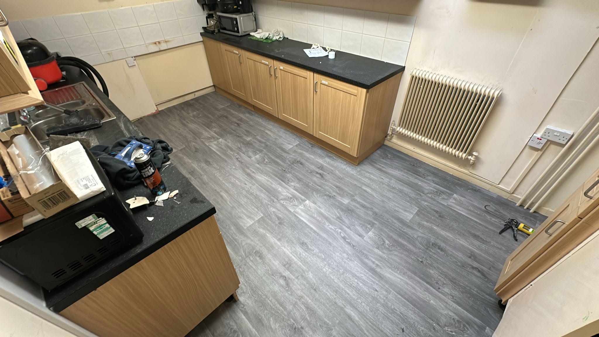 The same kitchen after: grey wood-plank vinyl laid throughout