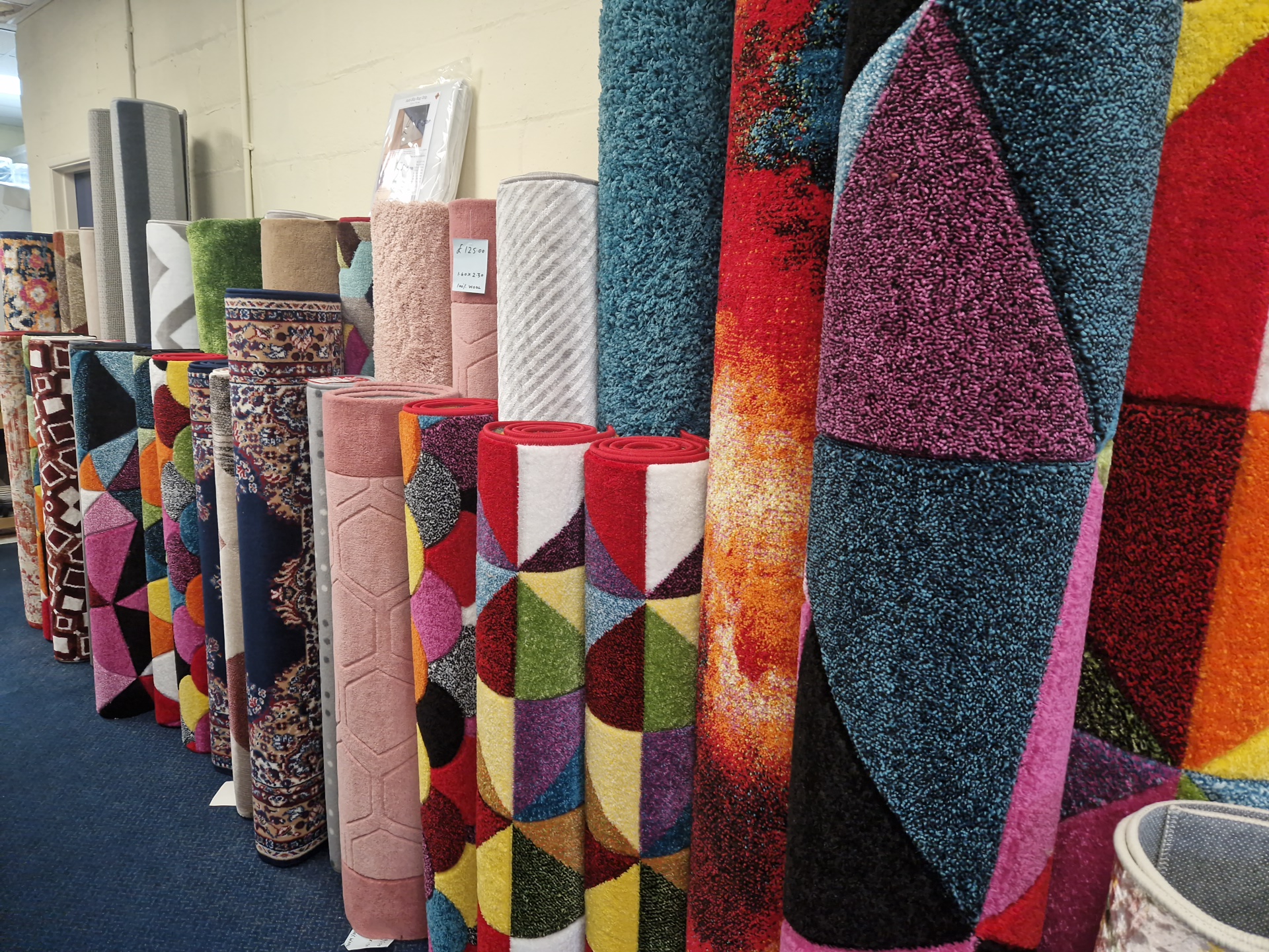 A row of rolled rugs in bright geometric and shaggy designs