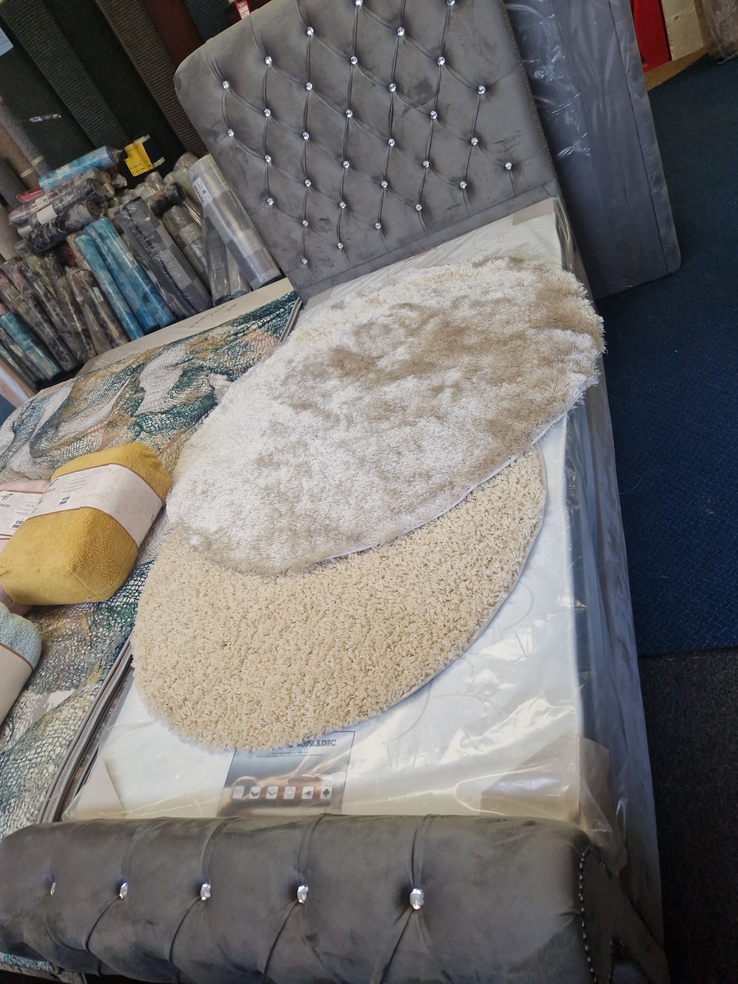 Grey upholstered bed with a studded headboard and soft rugs