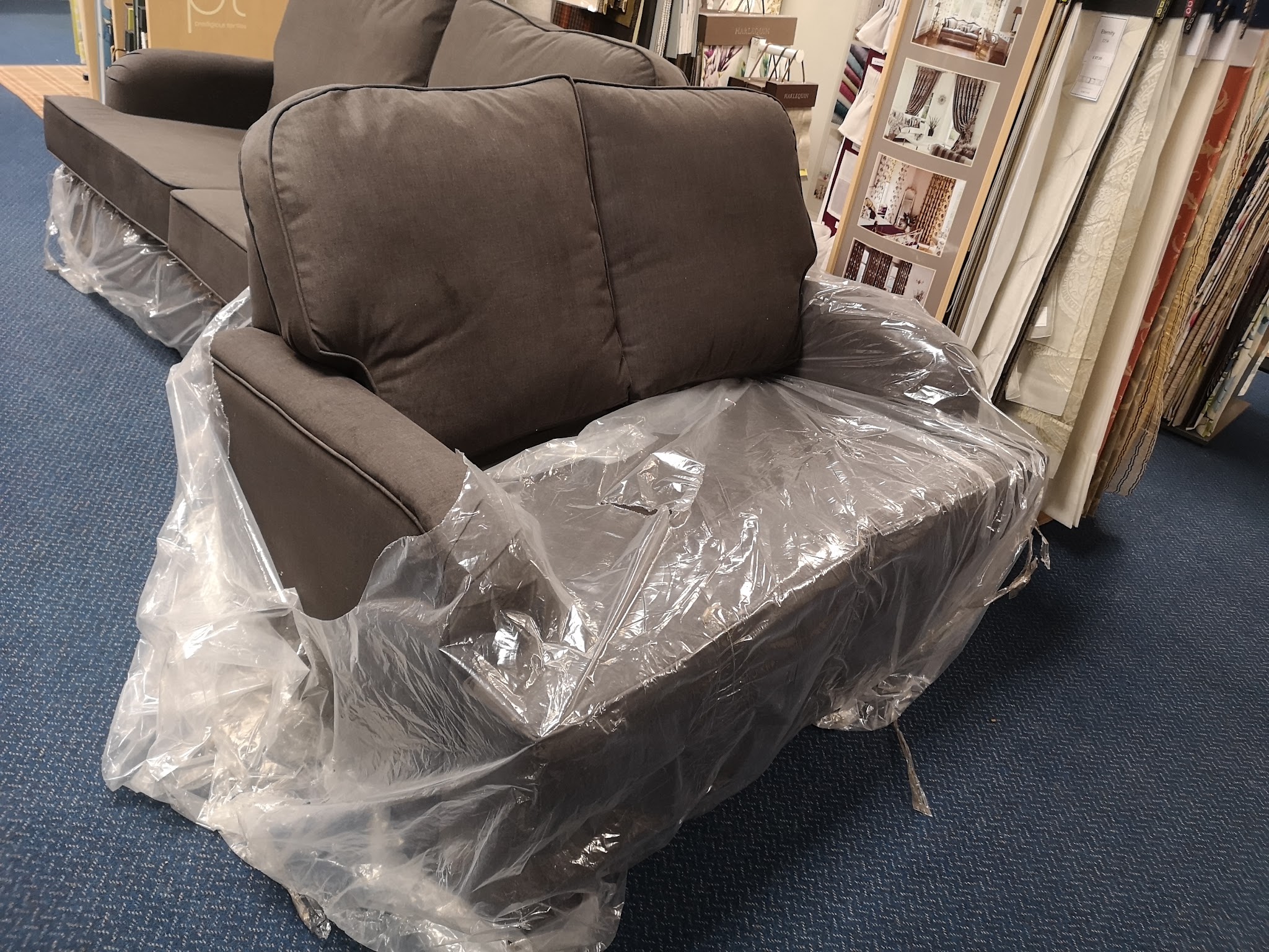Grey sofa still in its wrapping, fresh in the shop